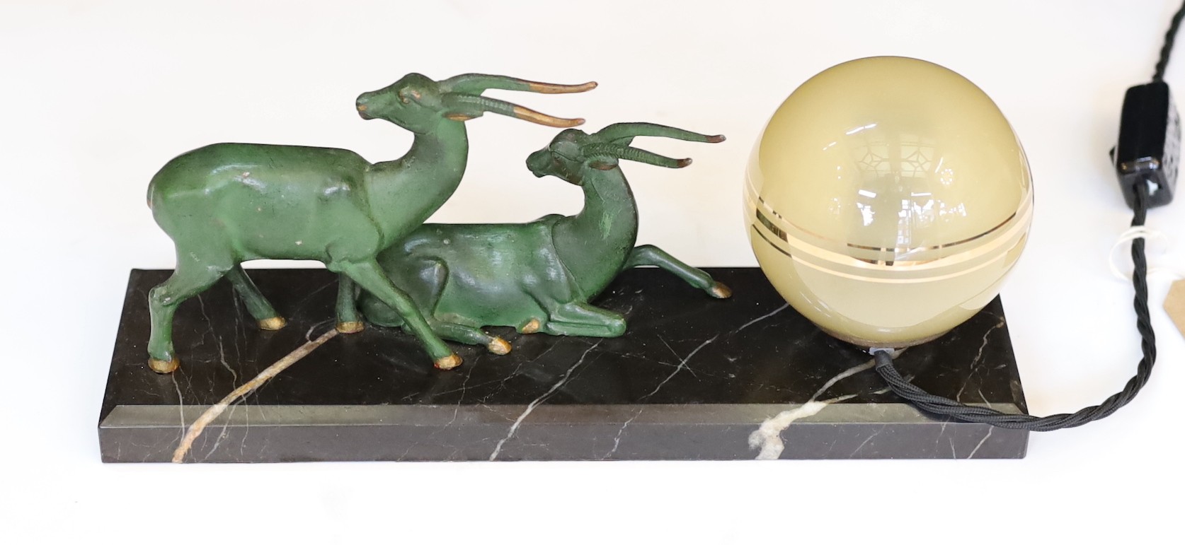 An Art Deco French bronze spelter and marble gazelles table lamp with etched spherical shade, height 10cm. width 32cm